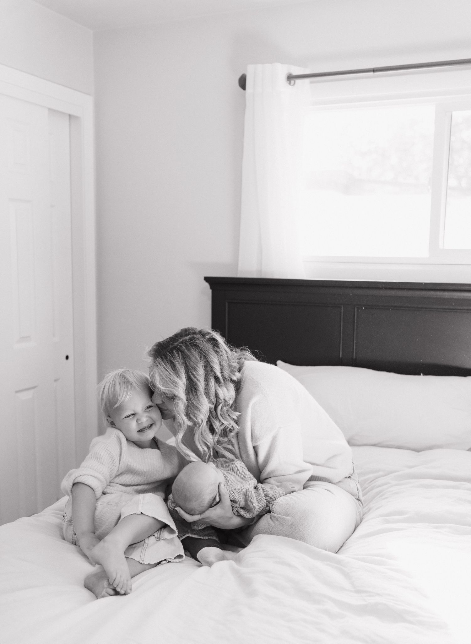 A mother and child cuddling on a bed in a cozy, intimate moment.