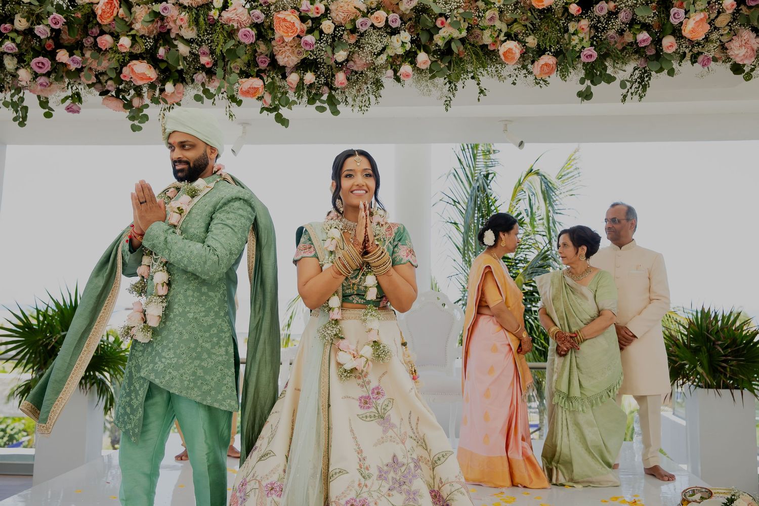 Wedding celebration under floral decorations with participants in traditional attire.