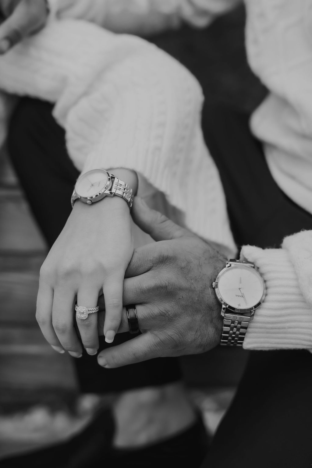 Close-up black and white photo showing hands with wedding rings and matching wristwatches.