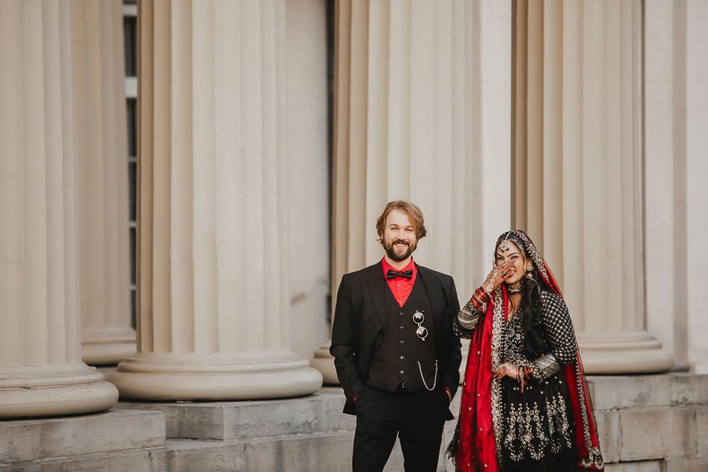 A formal event at an elegant columned venue with attendees in black and red attire.