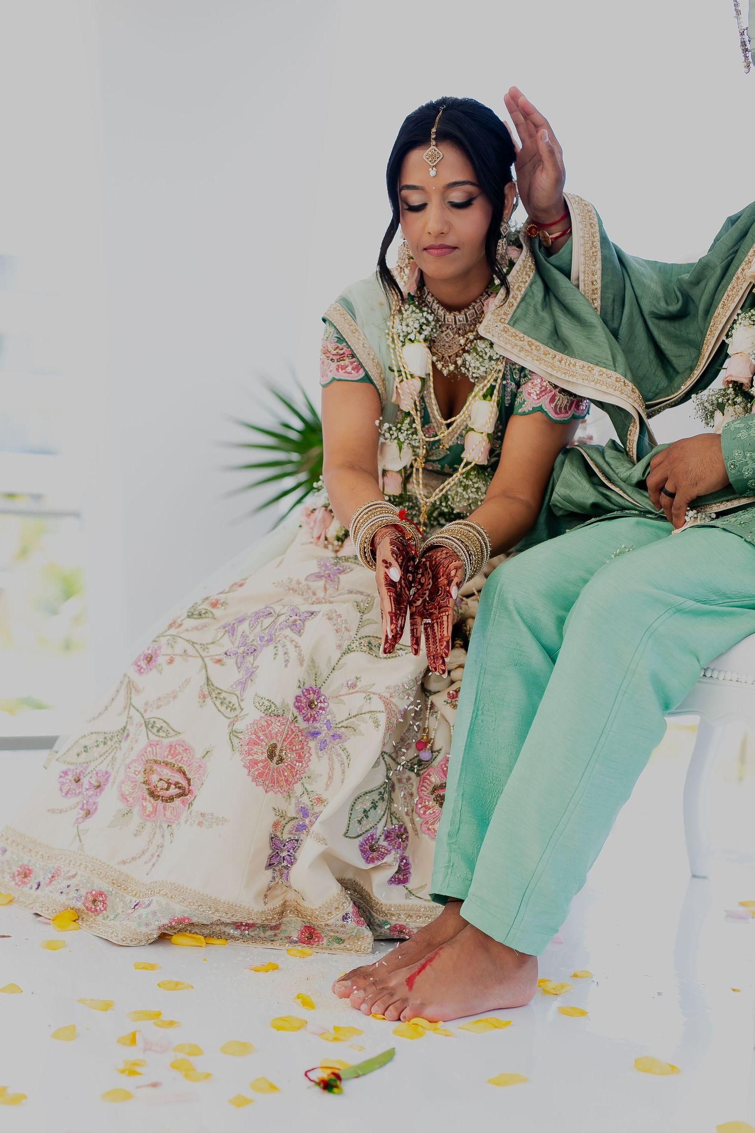 Bride in traditional Indian wedding attire showing intricate henna designs on her hands.
