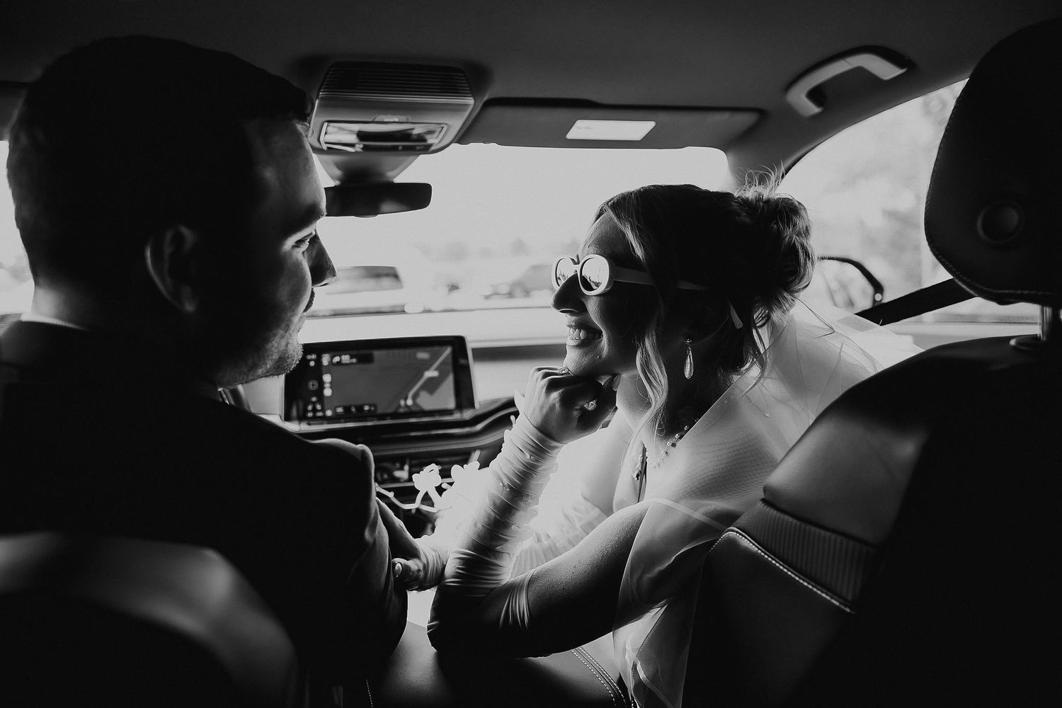 Dark silhouettes against a car window create a moody wedding day moment.