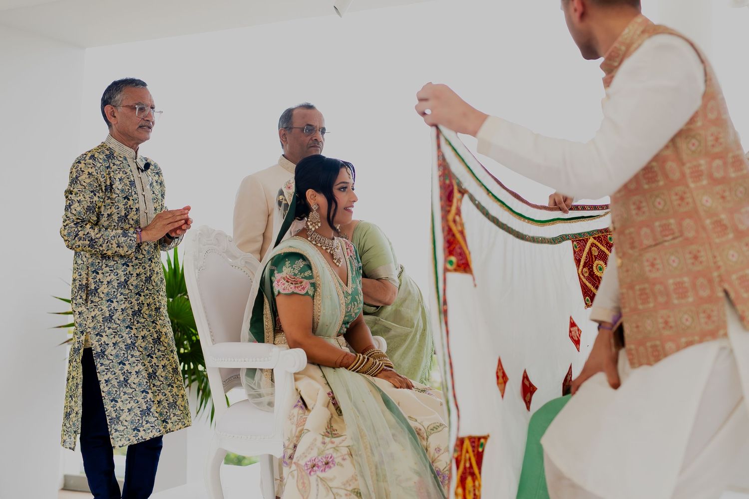 Family members participate in a traditional wedding ceremony ritual with decorative fabric.