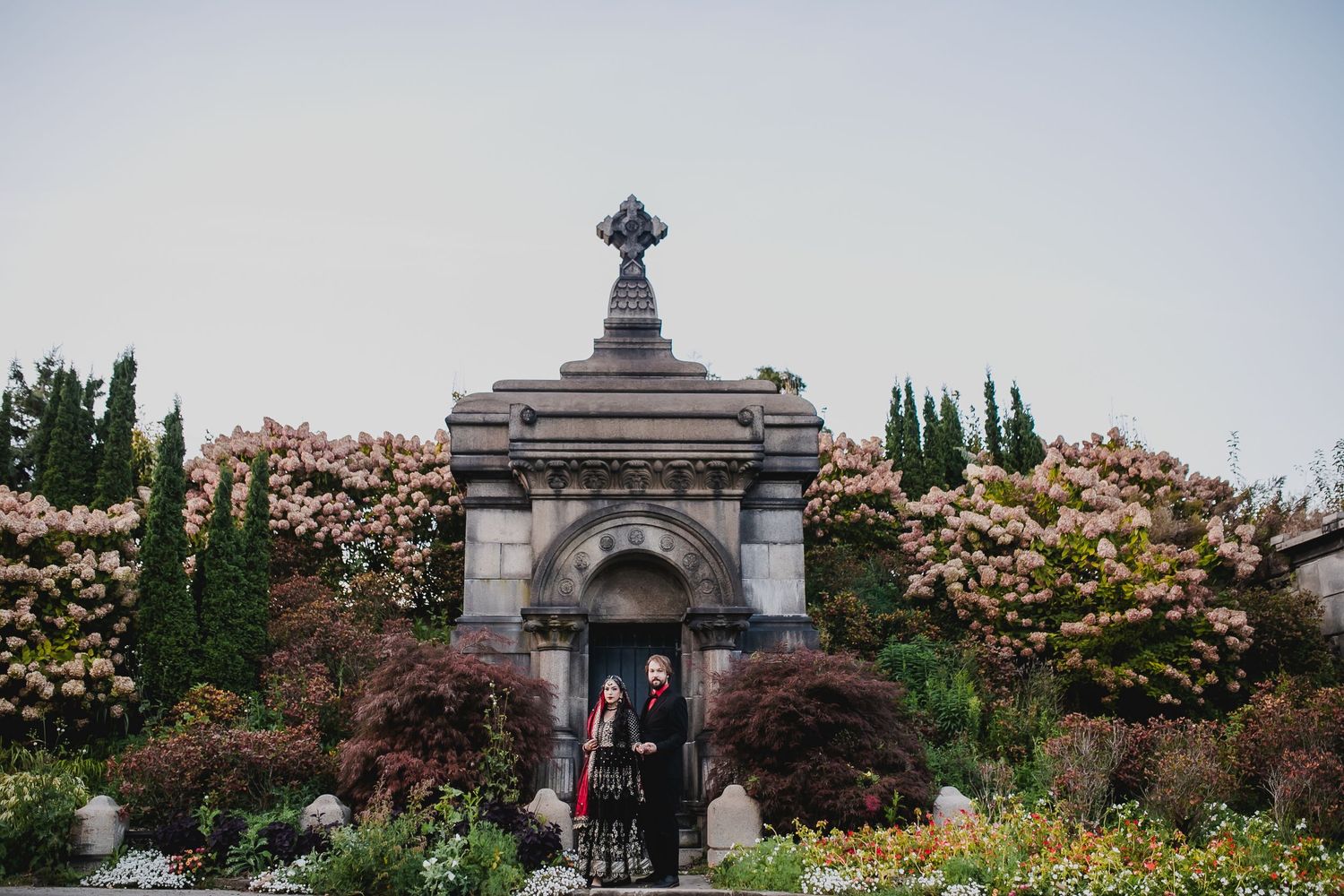 Wide garden view of a grand architectural venue with stone columns and flowering trees.