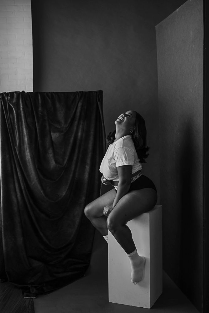 Artistic black and white photo series showing a figure in white against dark backdrop on geometric white pedestal.