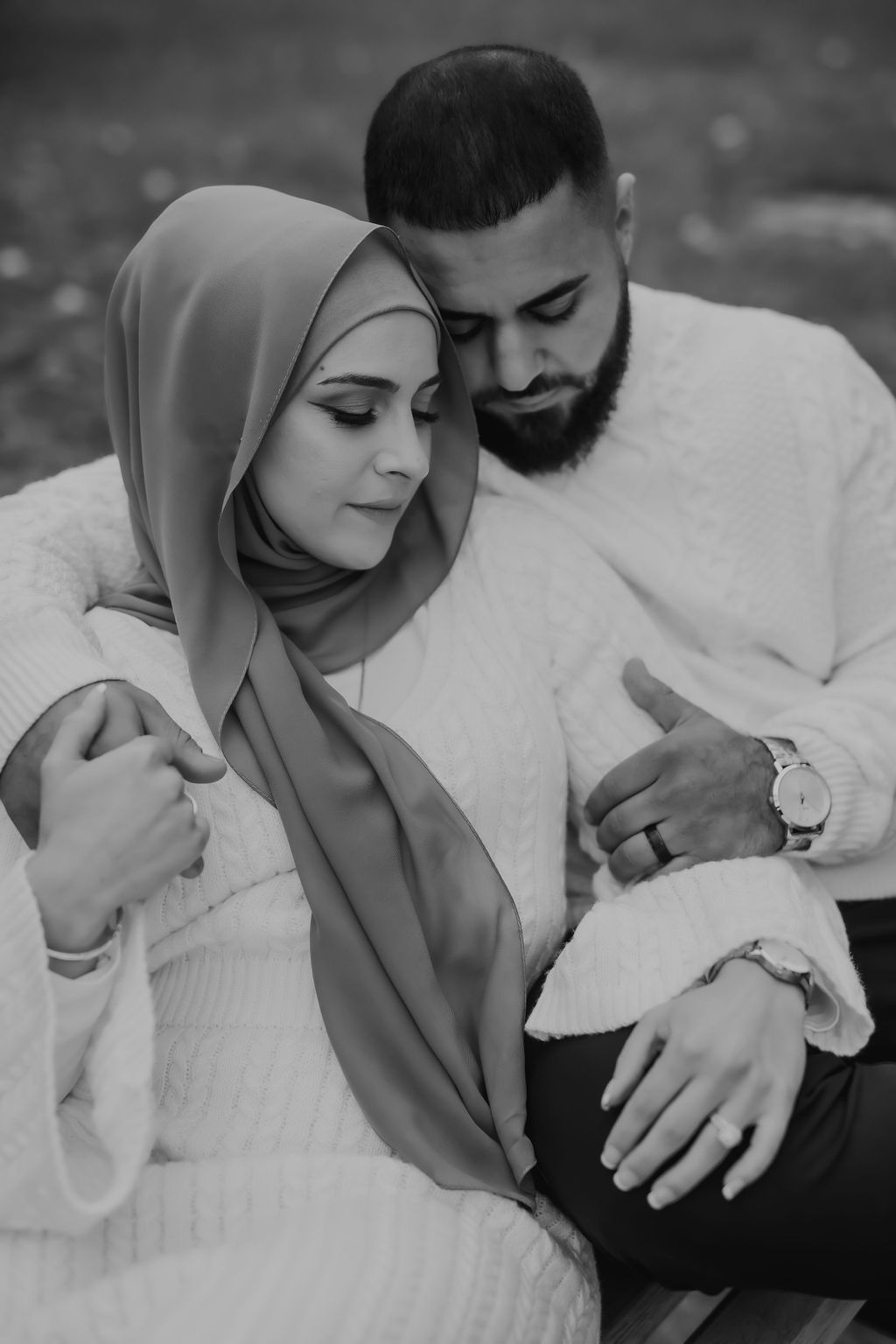 Black and white portrait of a couple in white sweaters sharing an intimate moment together.