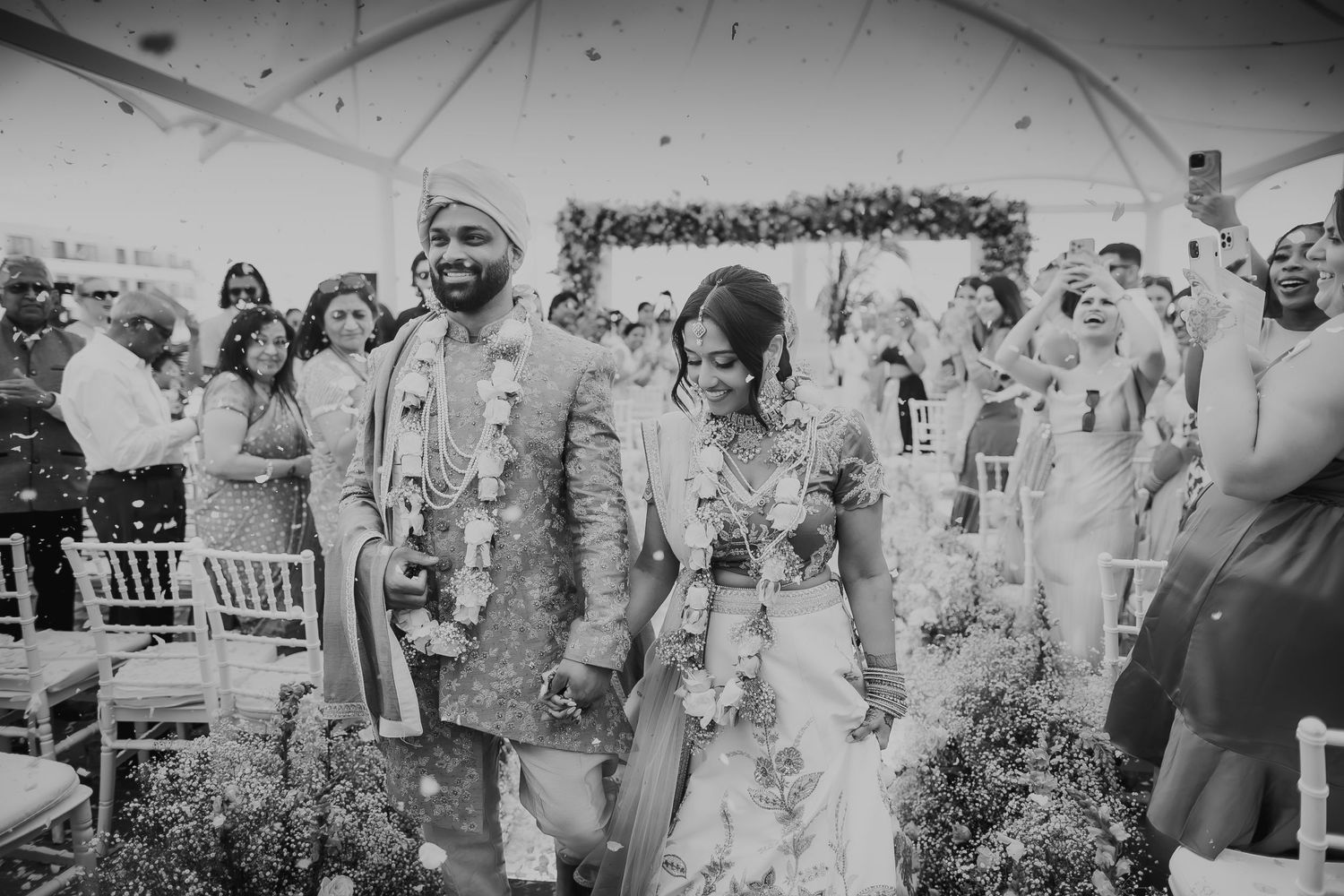 Wedding celebration with guests showering flower petals on couple during ceremony.