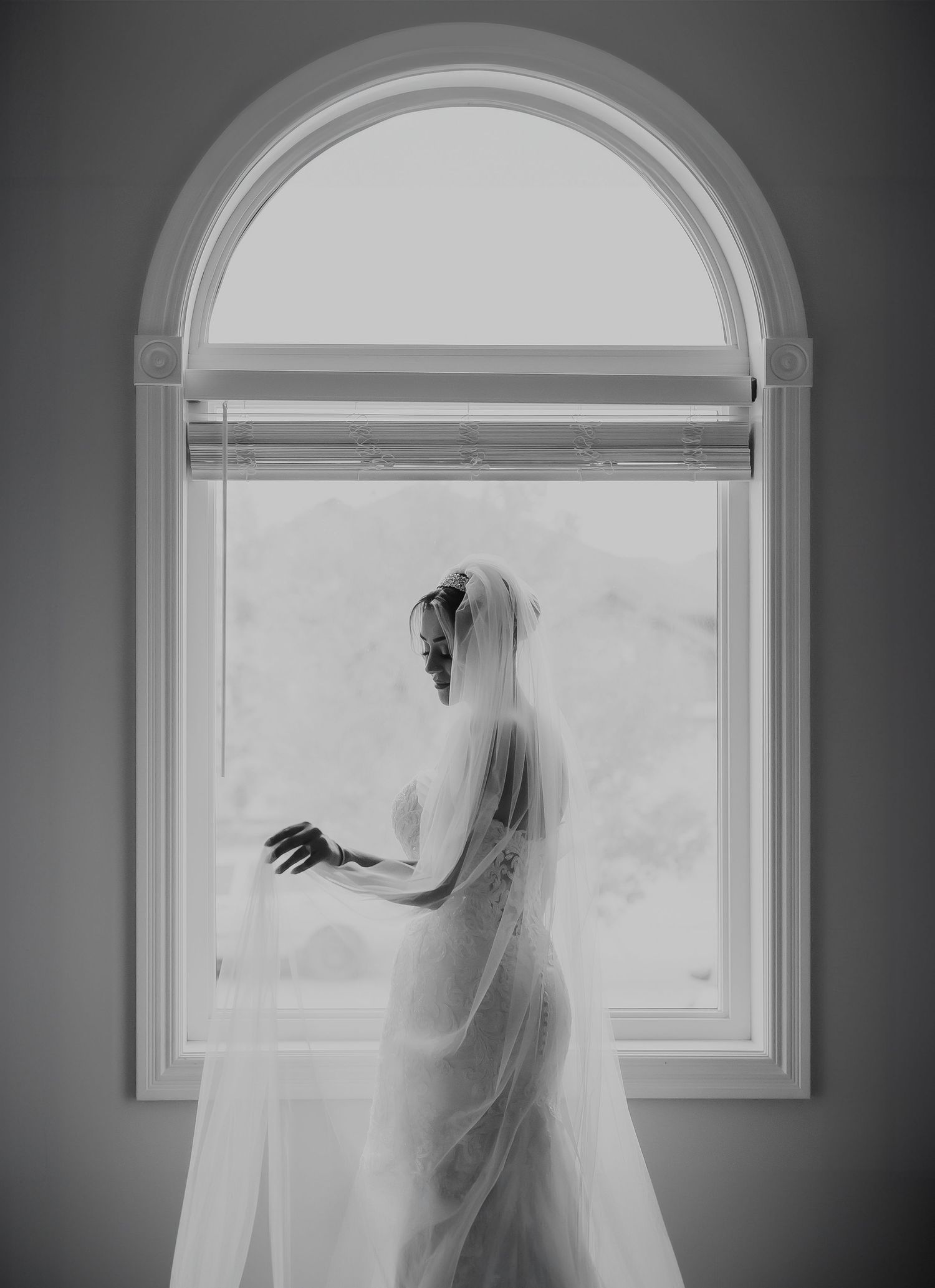 A black and white series of arched windows with flowing white curtains and veils creating an ethereal atmosphere.