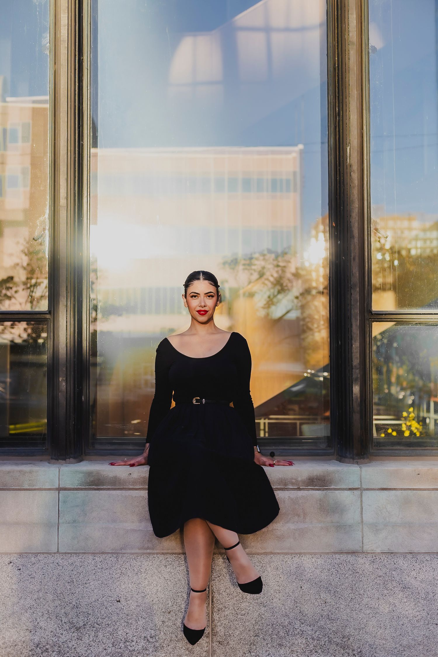 A series of four artistic fashion portraits showing a person in black clothing posing against a modern building exterior.