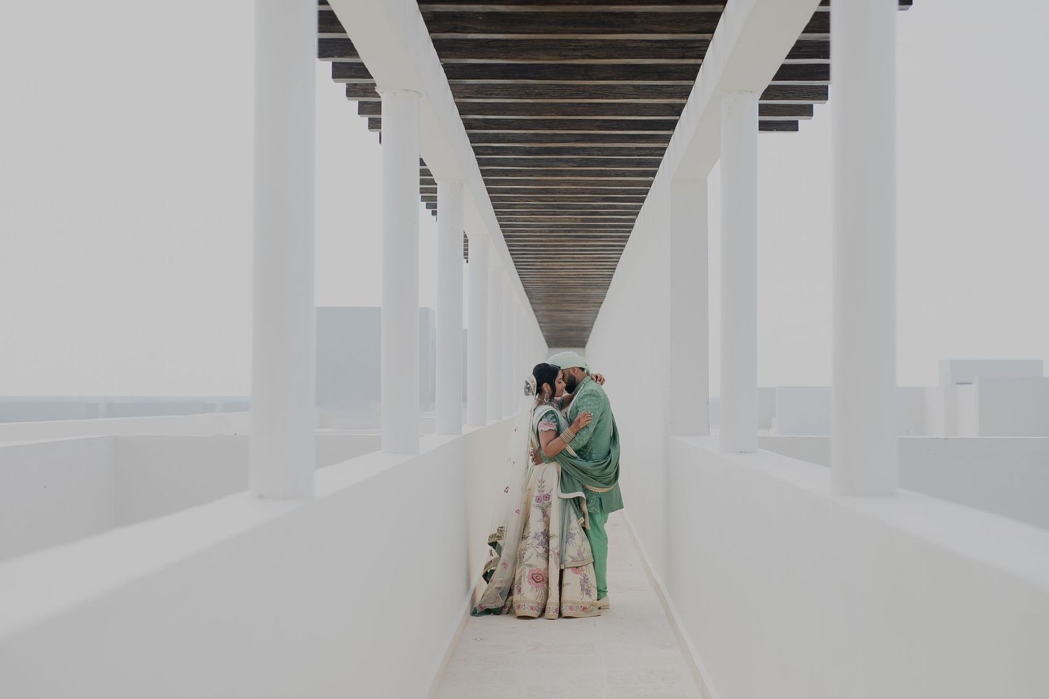A couple stands in a modern white hallway with dramatic architectural lines.