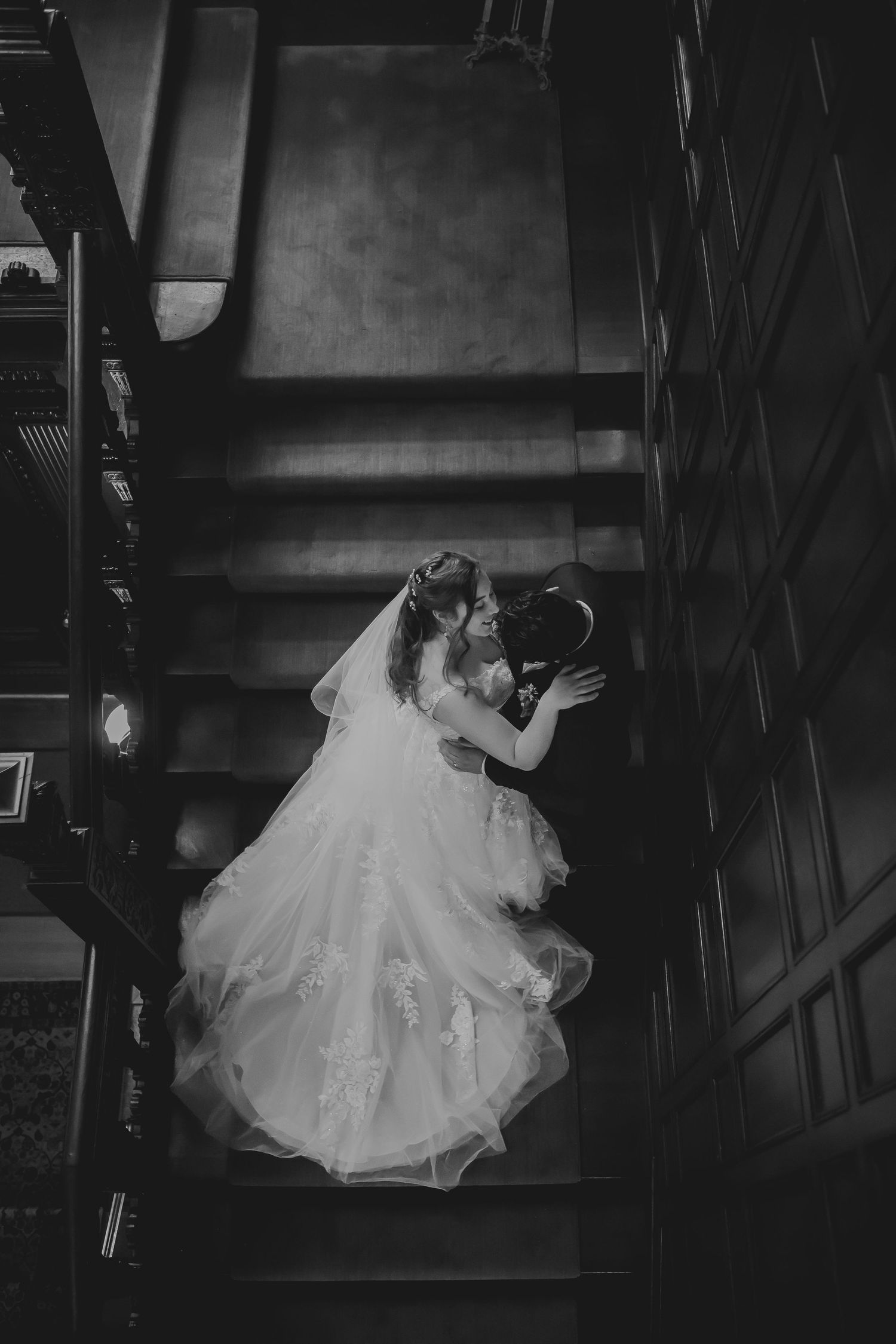 A romantic black and white photo series of a couple in wedding attire sharing intimate moments on a staircase.