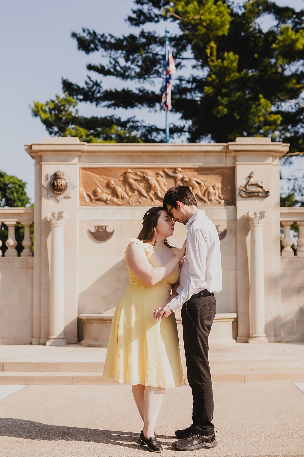 A romantic couple dances together on an outdoor terrace with decorative stone railings and trees in the background.