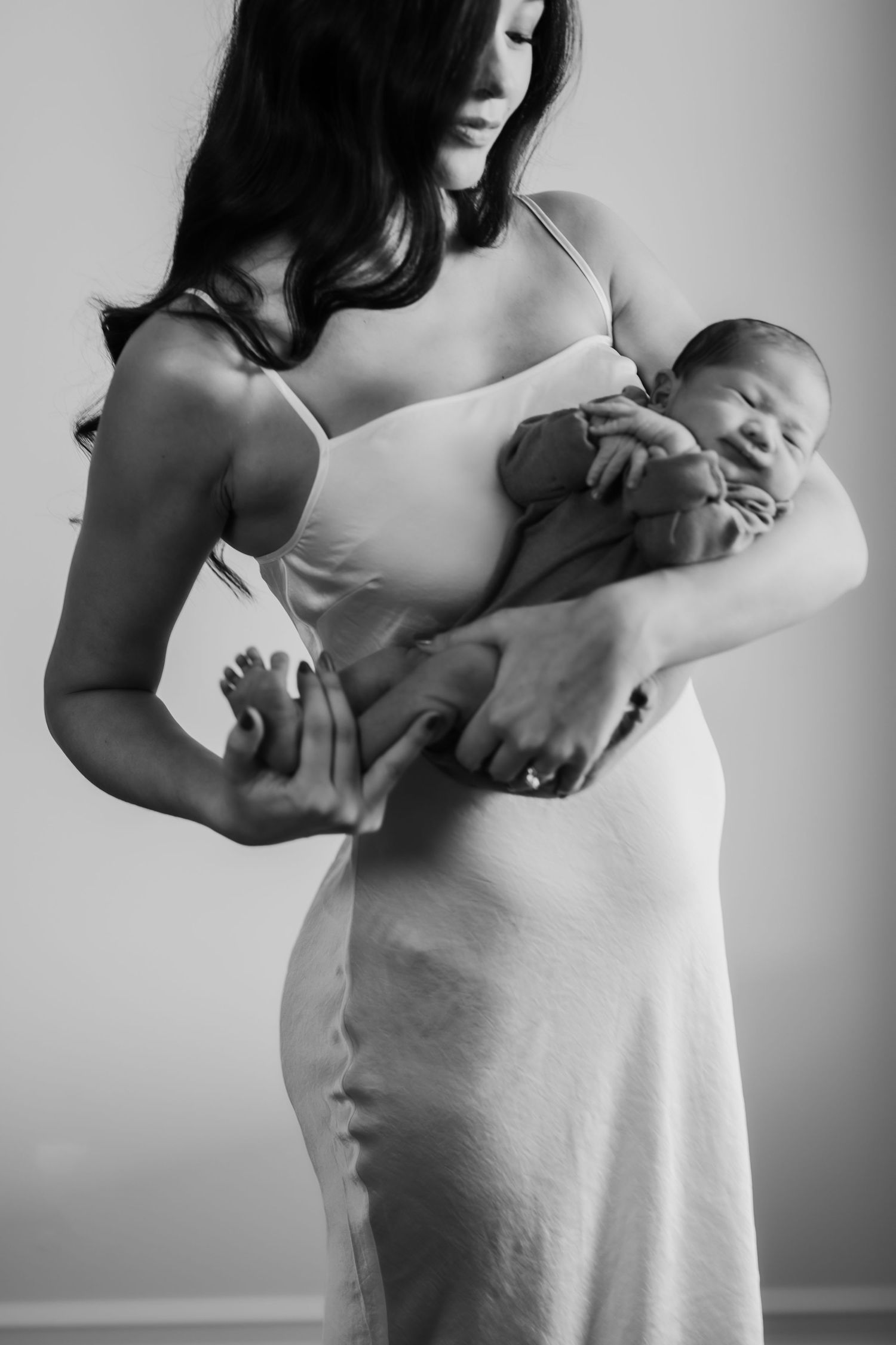 A black and white photo series showing a pregnant woman's growing belly over time in a white tank top.