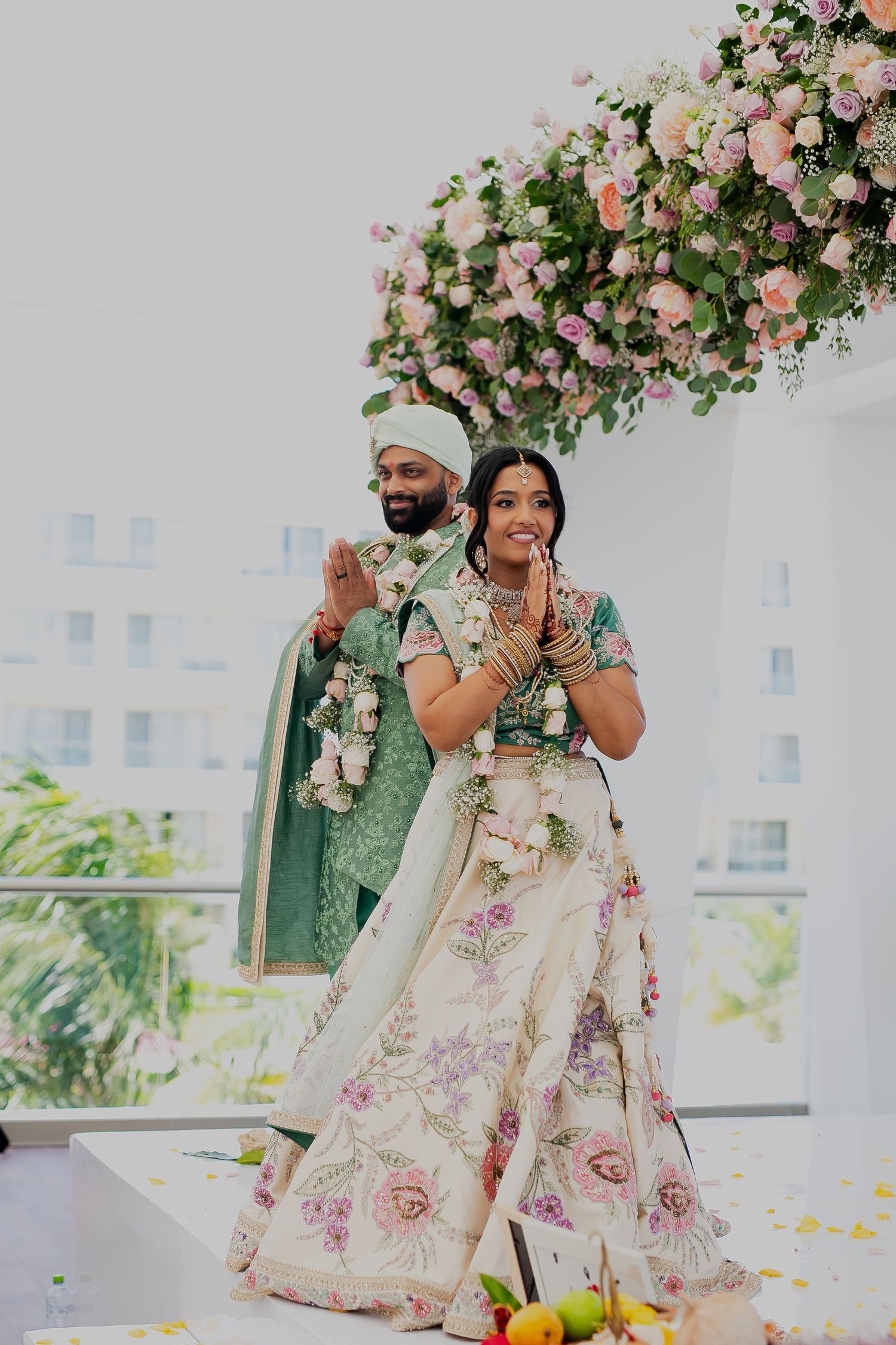 Couple poses under a beautiful pink floral arch during their wedding ceremony.