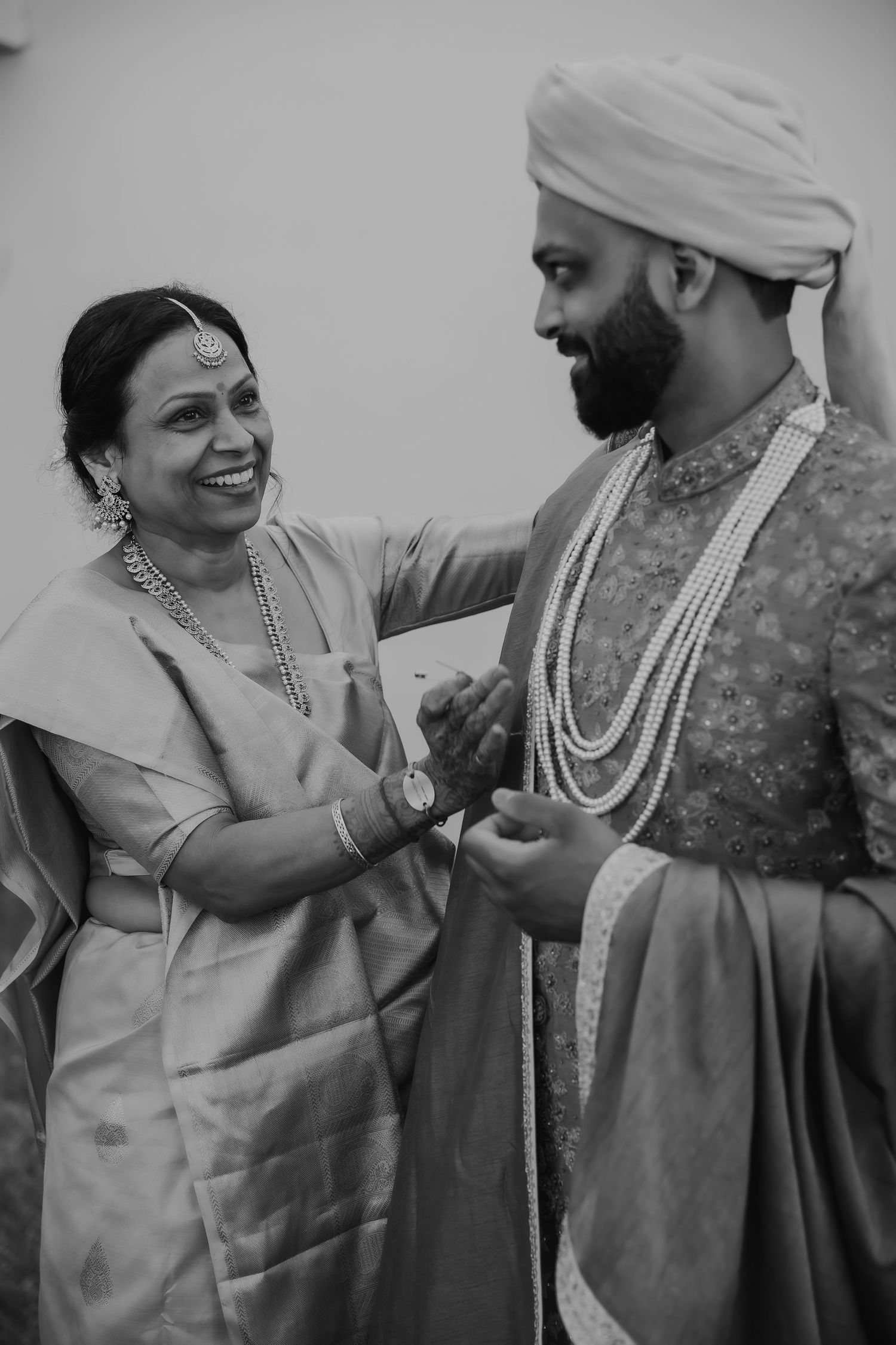 Black and white capture of heartwarming moment in traditional Indian wedding attire.