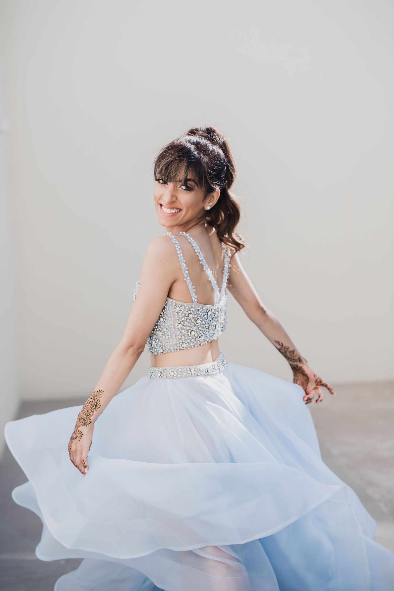A flowing white dress with sparkly straps twirls gracefully in a bright studio setting.