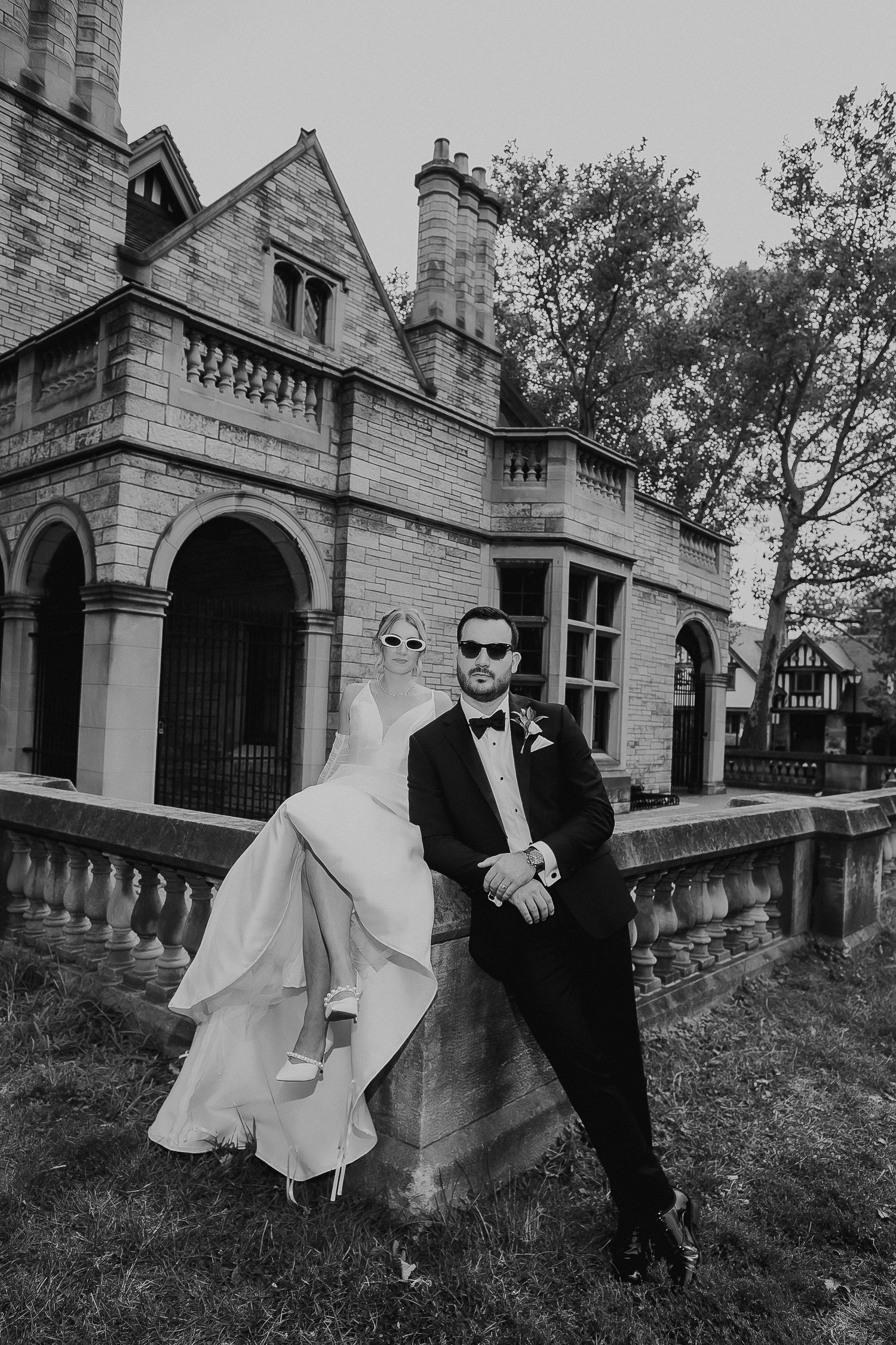 Black and white portrait of a couple in formal wear by historic architecture.