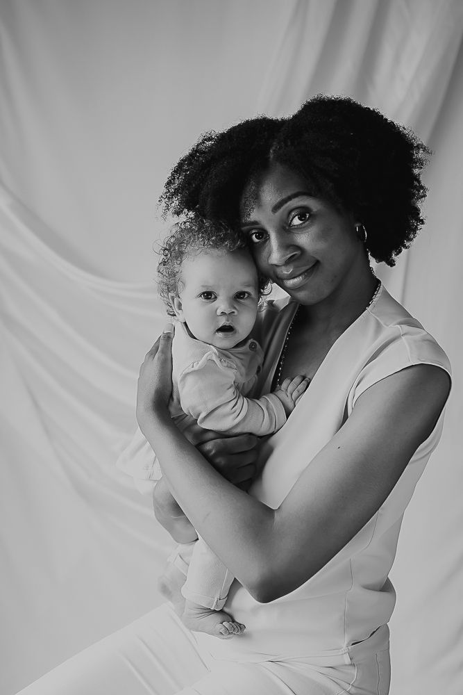 Black and white photos show intimate moments between a parent and baby against a white backdrop.