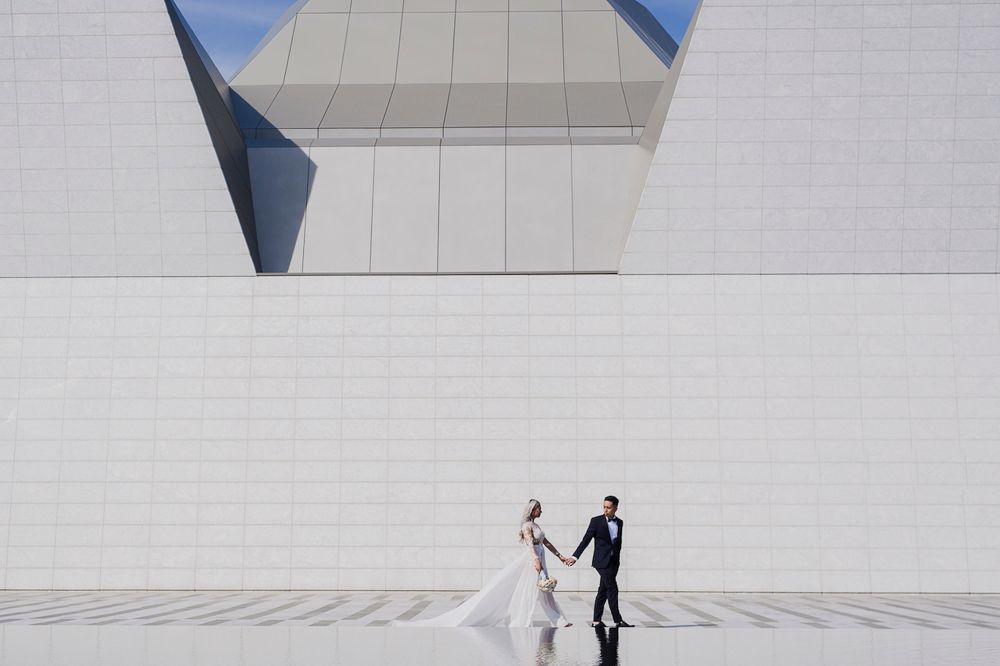 A sequence of wedding photos showing a couple walking through a modern minimalist white building interior.