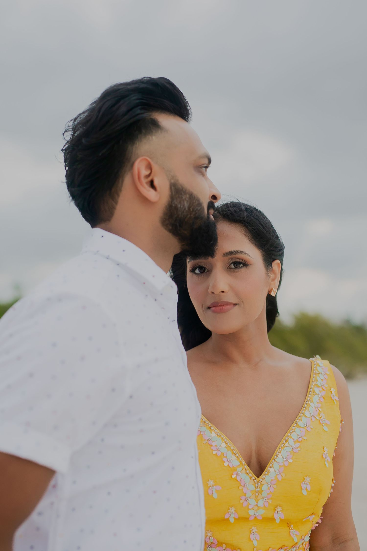A tender moment between a couple with one in a yellow embellished dress.