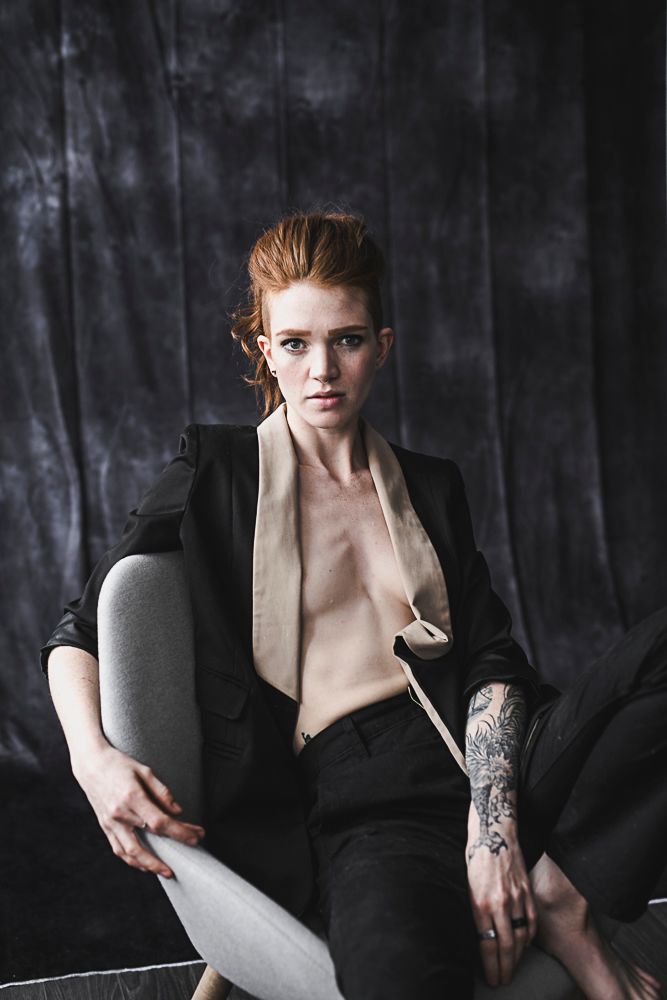 Moody fashion photography series featuring model in black blazer with tattoos against dark textured backdrop.