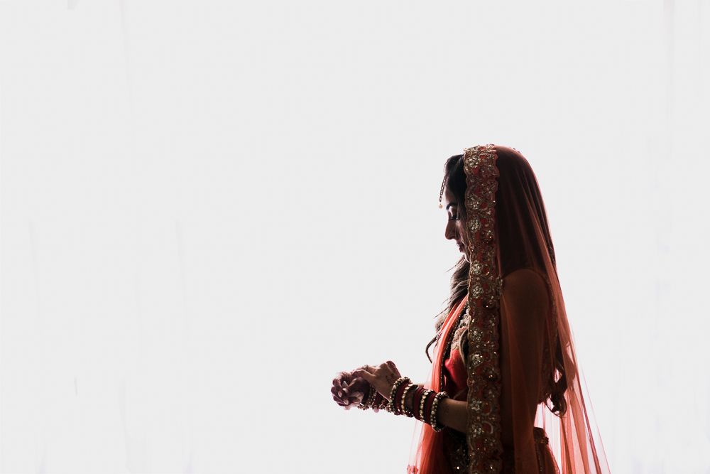 Side profile silhouette of bride in traditional Indian wedding attire with detailed embroidery and flowing veil.