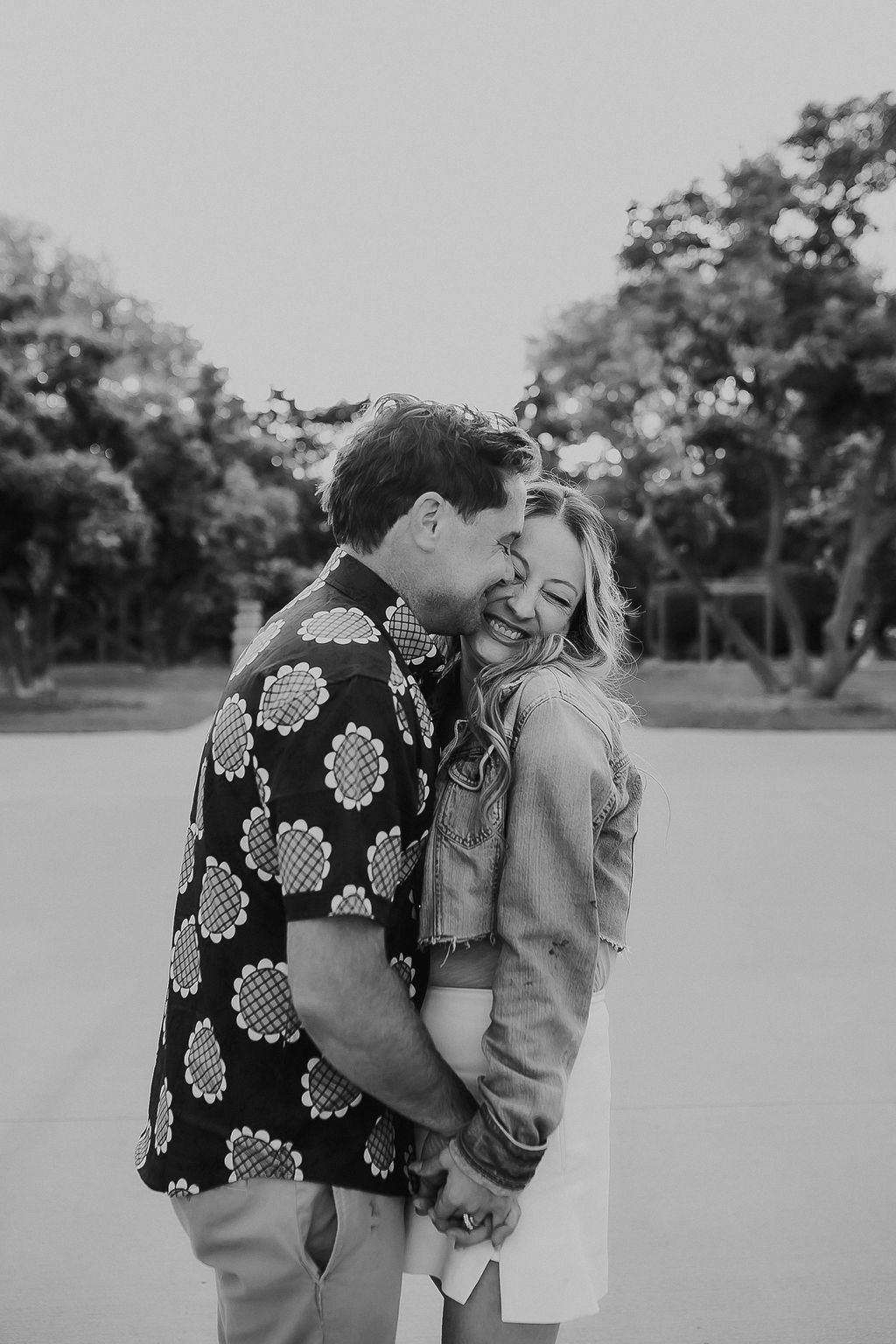 Black and white romantic photo series of a couple embracing and laughing together in an outdoor setting.