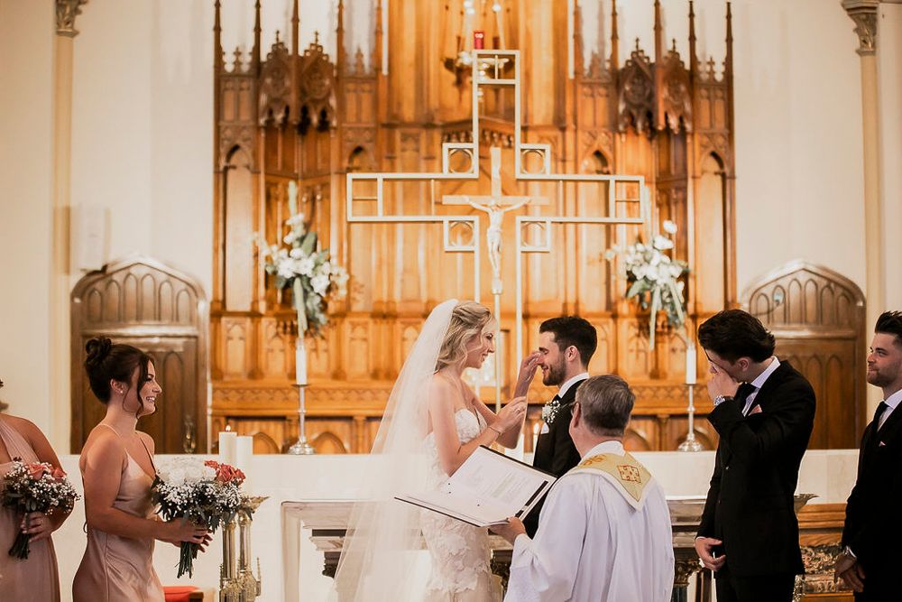 Wedding ceremony taking place in a traditional church sanctuary with warm lighting and wooden altar details.