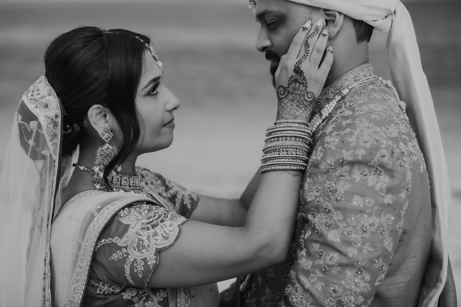 An intimate black and white portrait of a couple in traditional South Asian wedding attire.