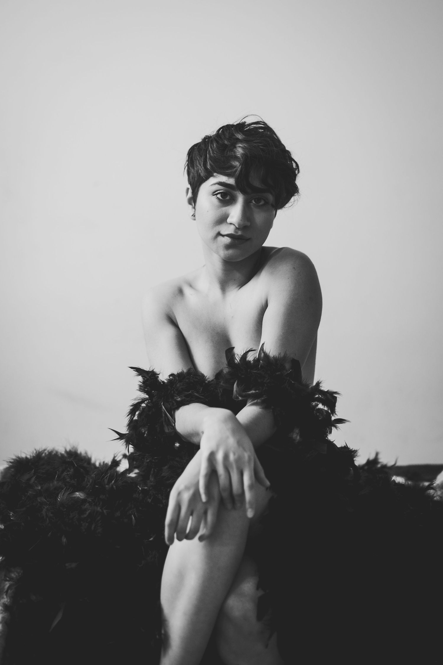 Black and white portrait of a woman with short dark hair posing gracefully with feather boa wrap.