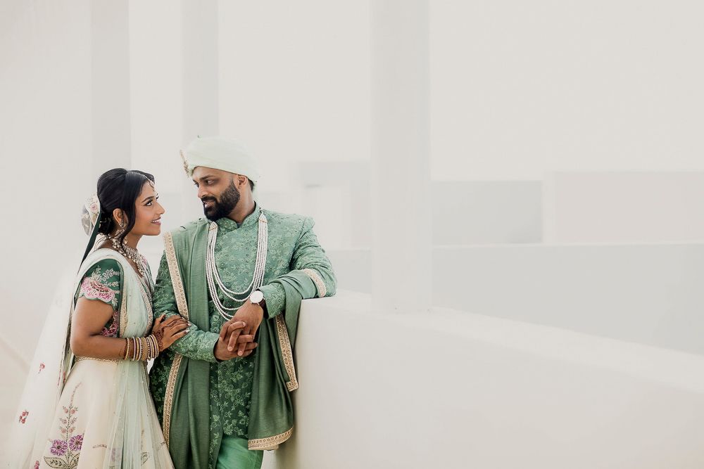 Couple in coordinating mint green outfits sharing intimate moments during their wedding photoshoot.