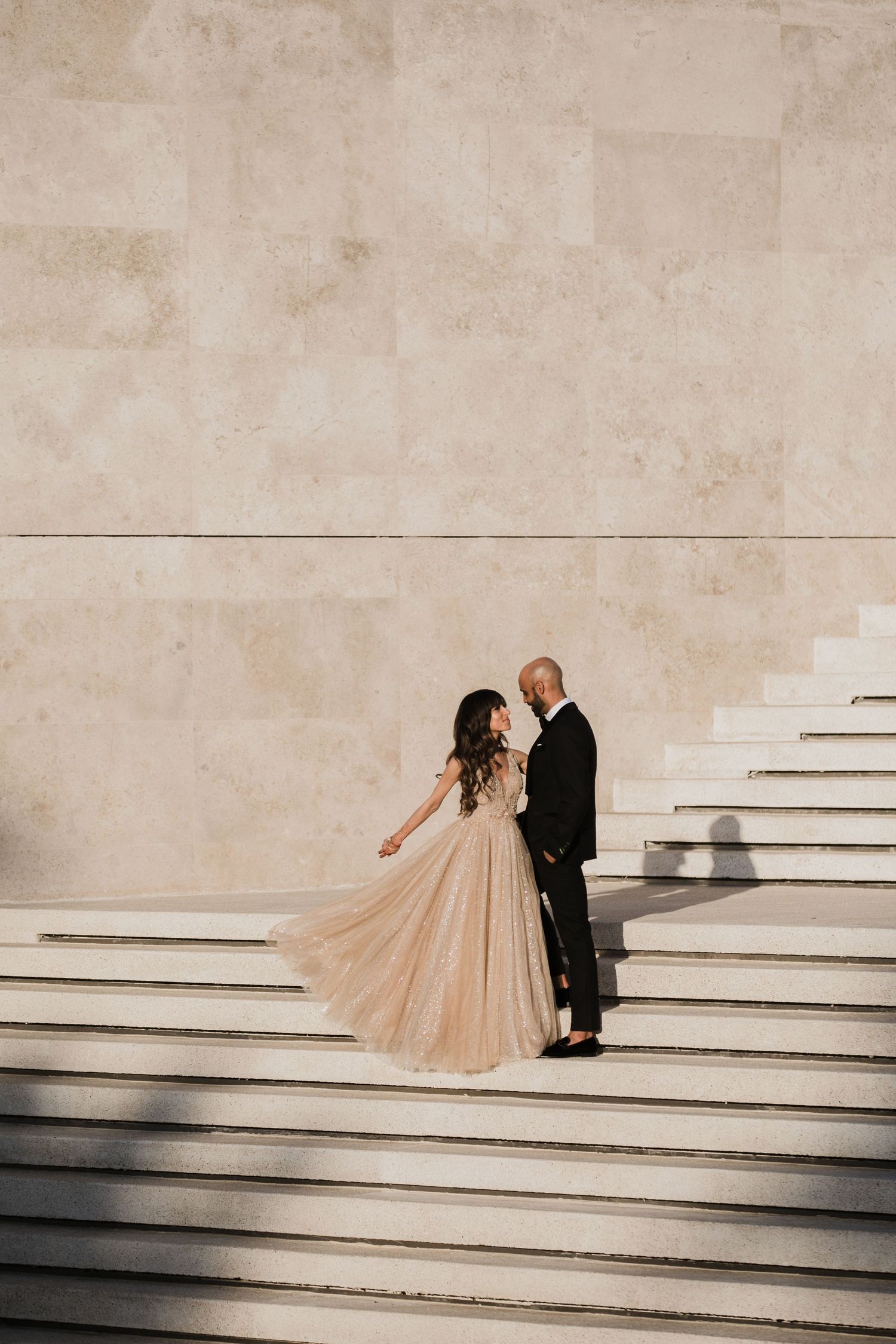 A couple in formal wedding attire ascending white stone steps in a romantic sequence of photos.