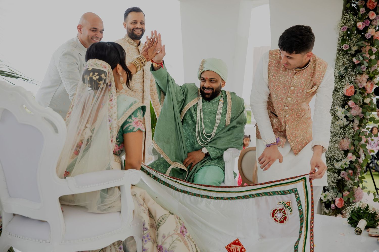 Wedding ceremony participants hold a traditional decorated white cloth during festivities.