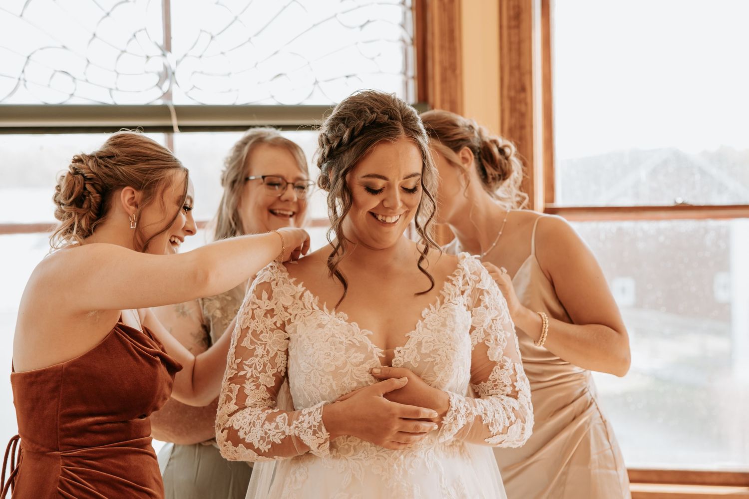 Wedding party shares joyful laughter together in a sunlit room.