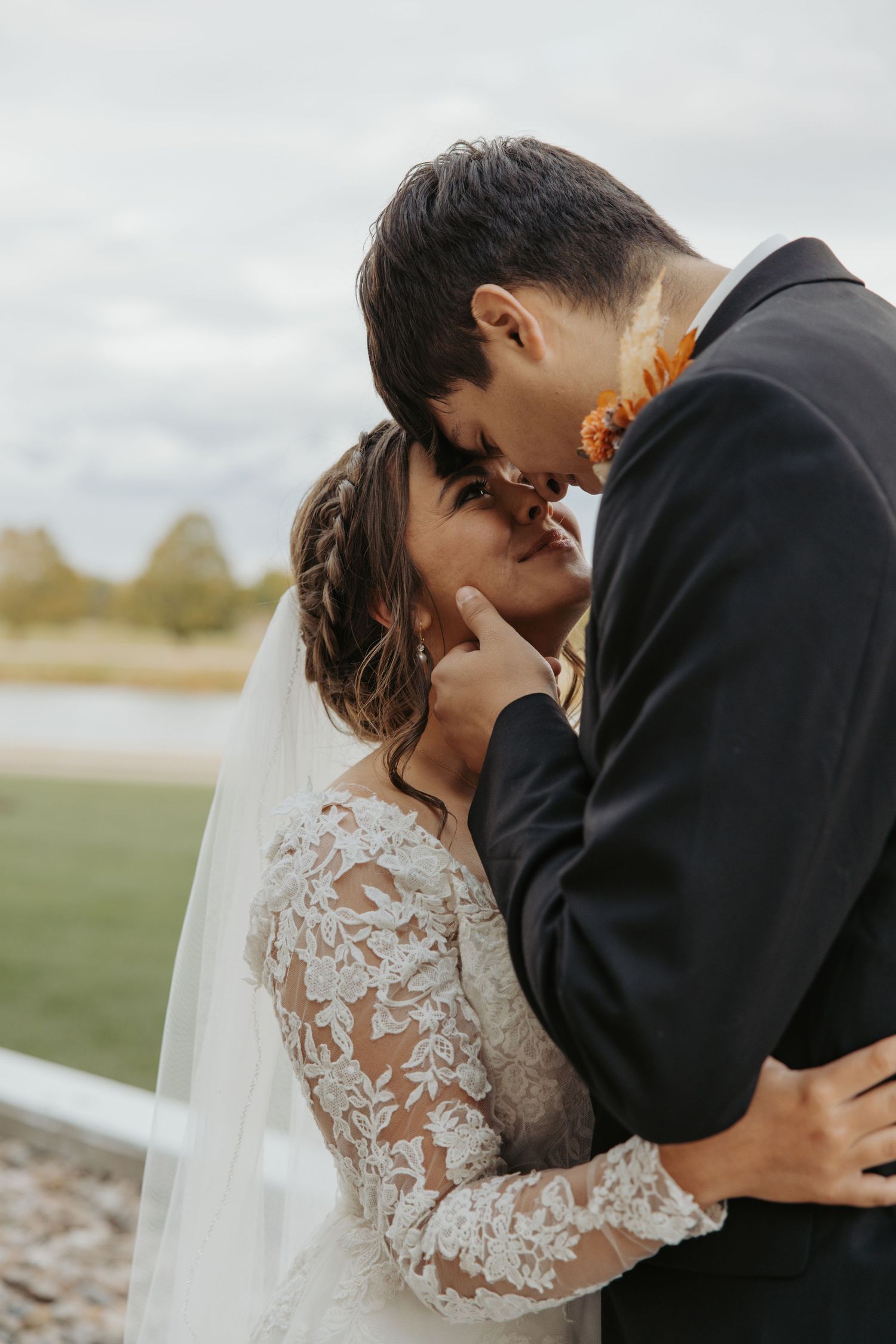 Tender moment between newlyweds embracing outdoors during wedding photoshoot.