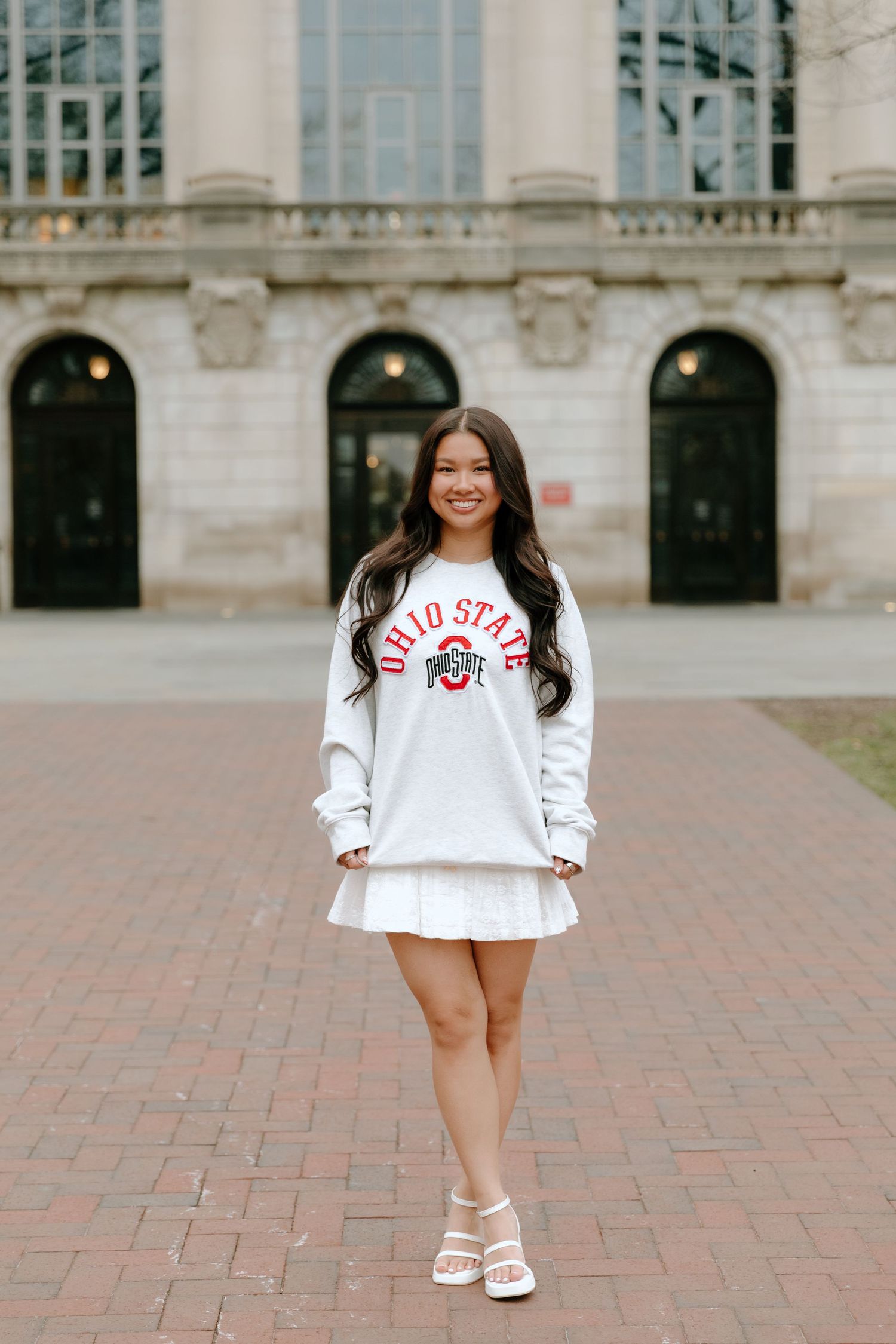 A series of five photos showing someone in a white Ohio State sweatshirt posing on brick pavement in front of a building.