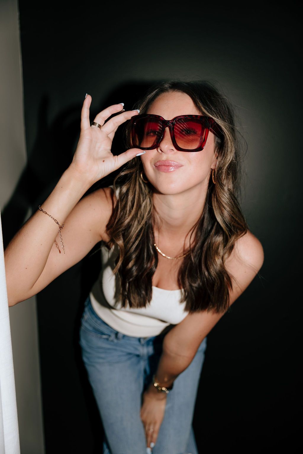 Person in red sunglasses and jeans strikes playful poses against dark background in photo collage.