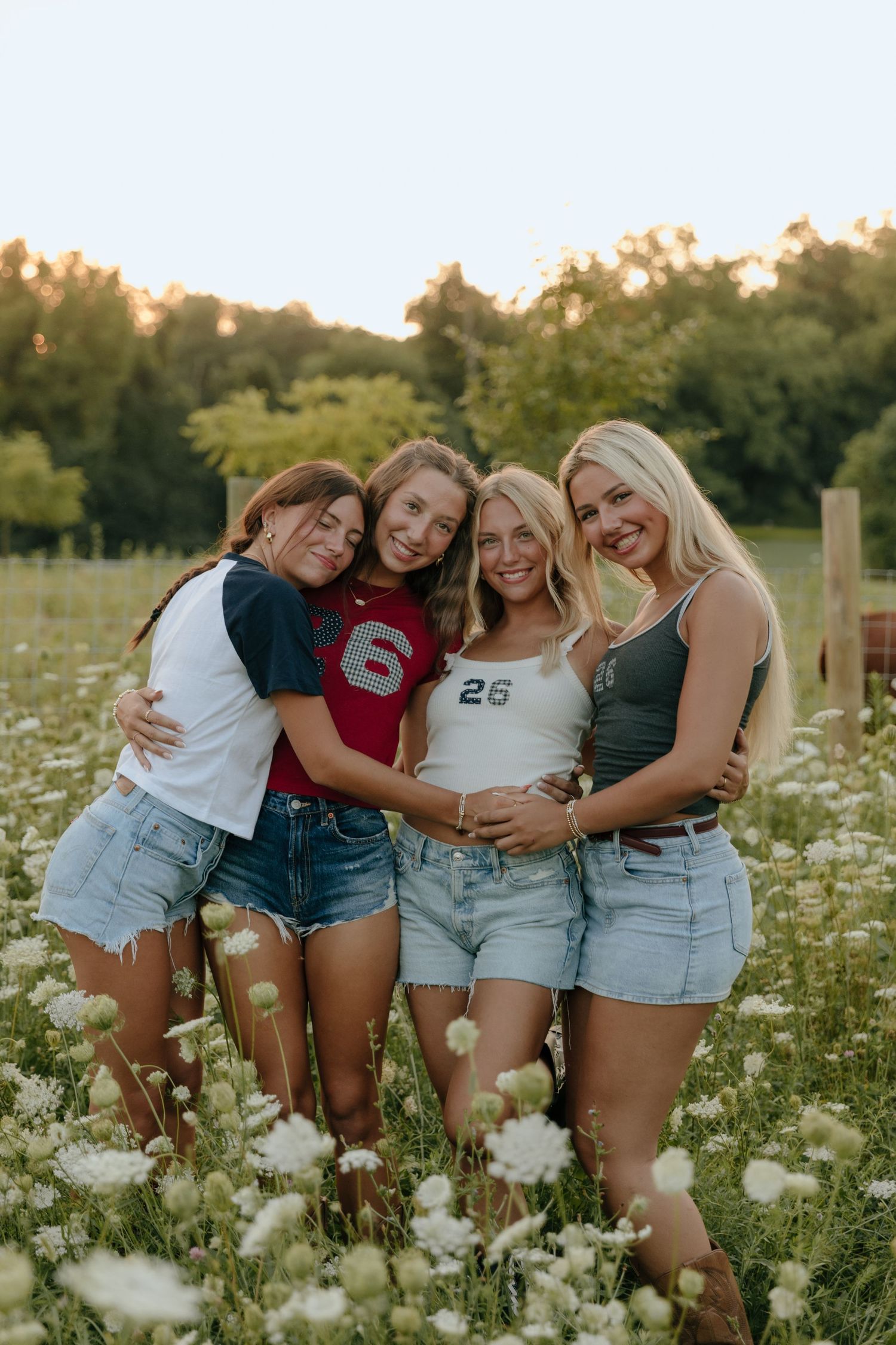 A group of friends laughing together in a summer wildflower field during golden hour.