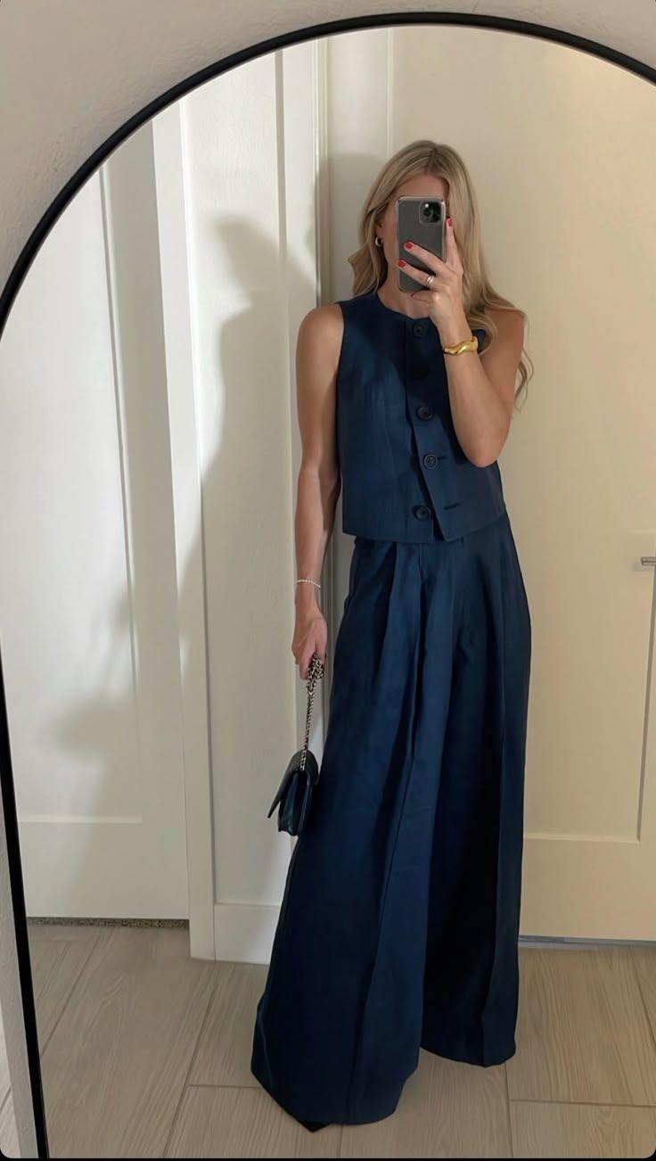 Mirror selfie showing a sleeveless navy blue dress with pleated skirt and button details.