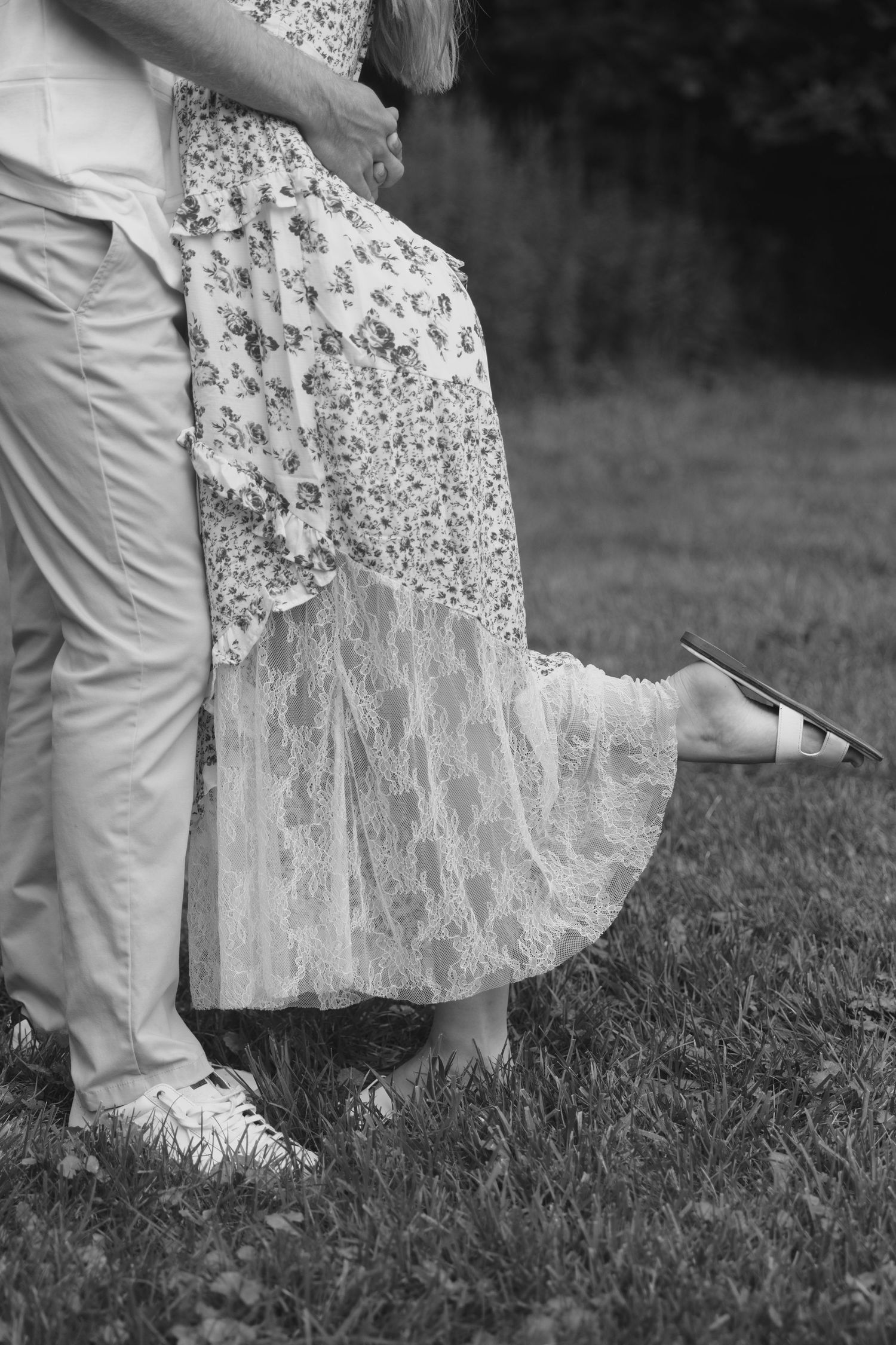 Close-up of floral lace dress and khaki pants during romantic moment on grass.