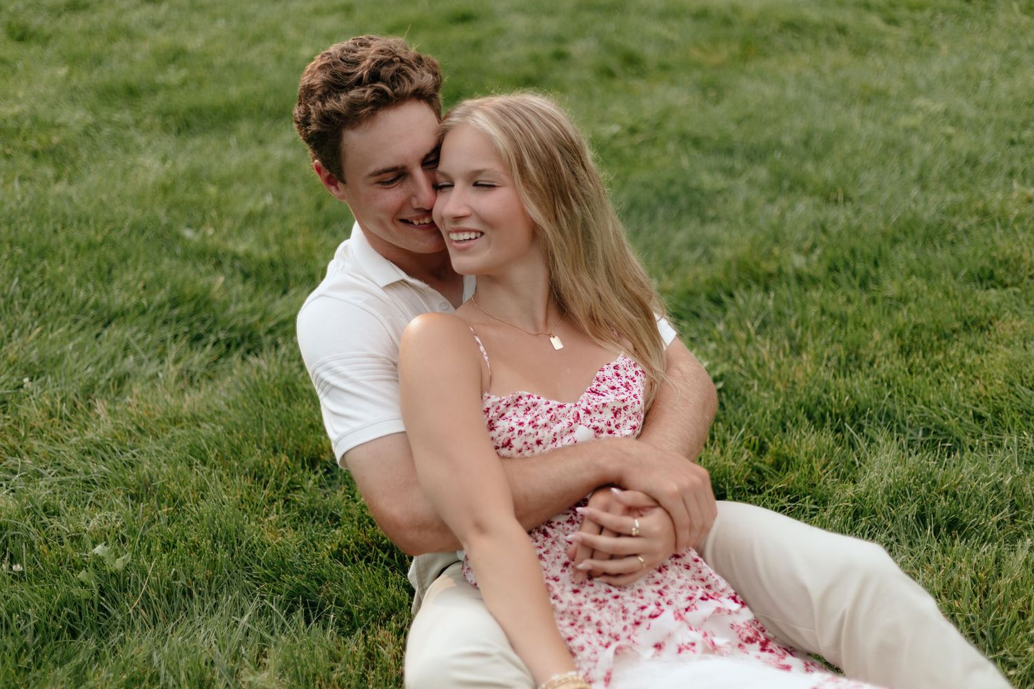 Romantic couple portrait session on lush green grass in summer attire.