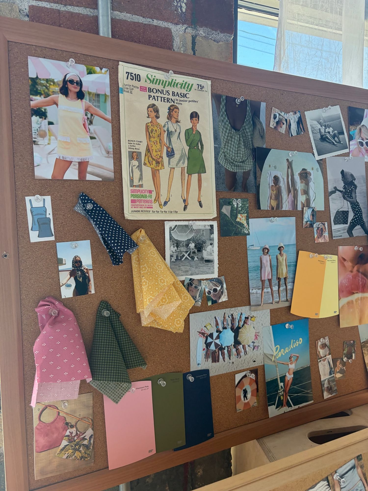 A vintage cork mood board displaying a Simplicity sewing pattern, retro fashion photos, fabric swatches, and colorful paper samples.