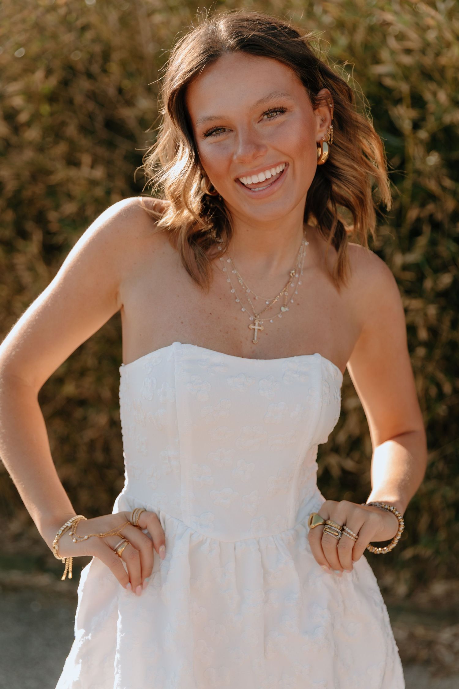 A person in a white strapless dress poses outdoors in a series of candid shots against a natural background.
