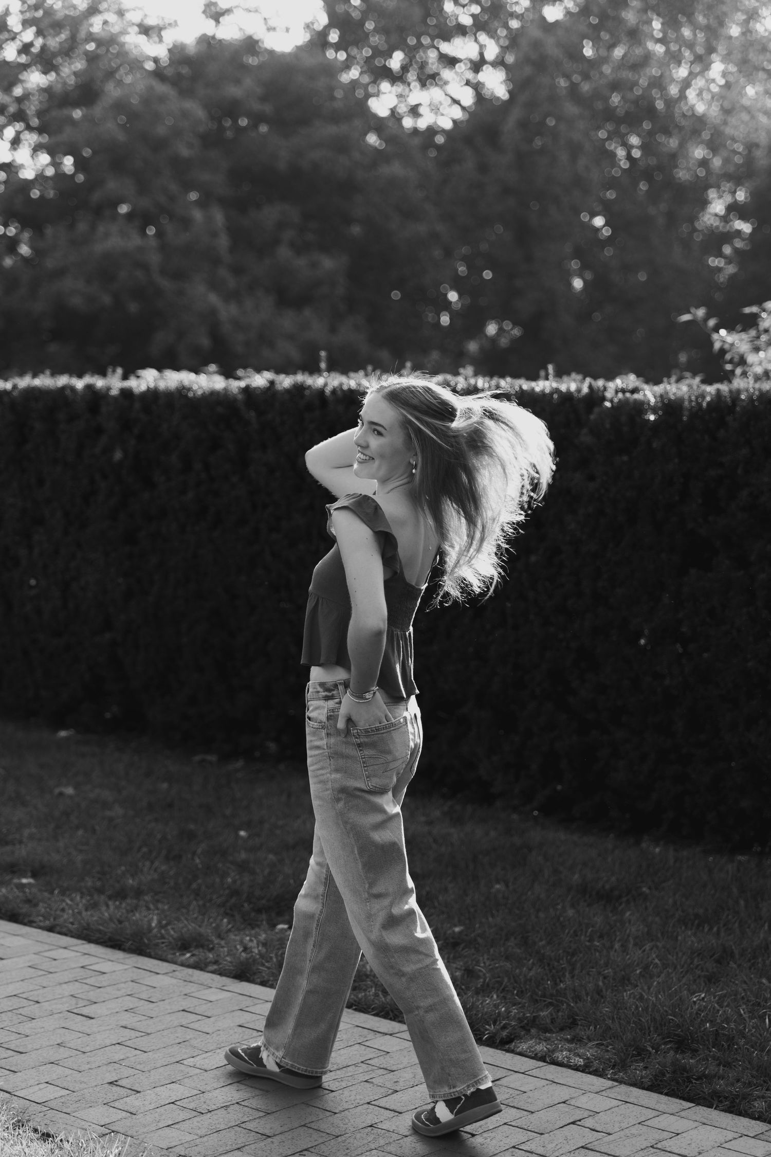 A sequence of black and white photos showing a person dancing energetically outdoors on a paved path.