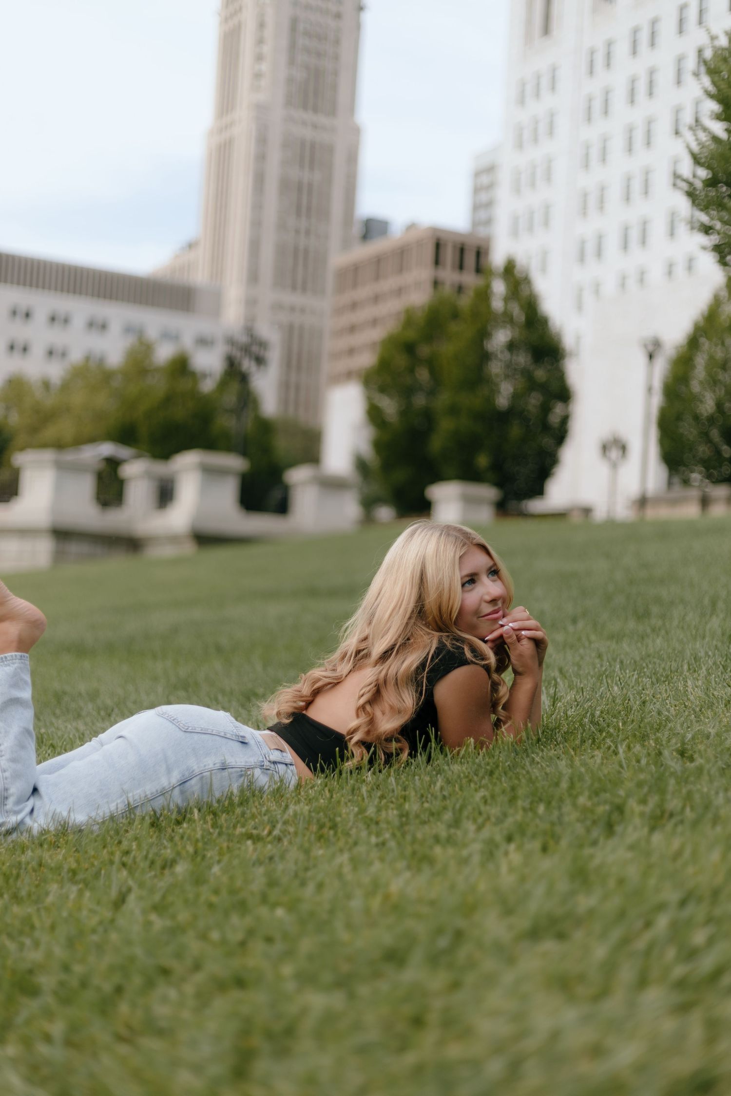 Person lying on green grass with historic building in background during outdoor photo session.
