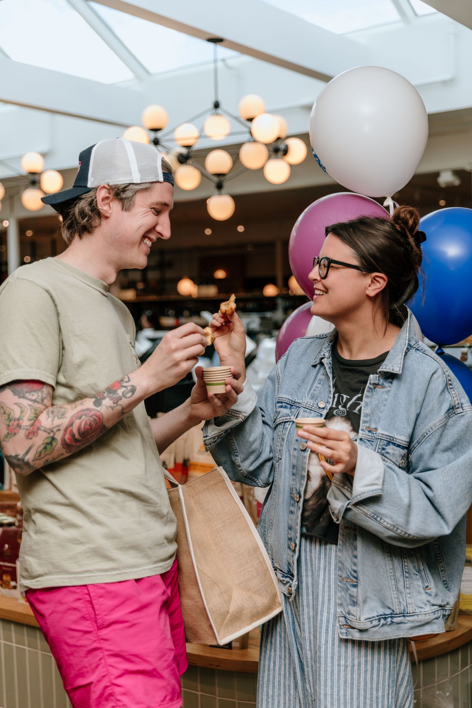 Friends sharing snacks and treats at a casual gathering with balloons in background.