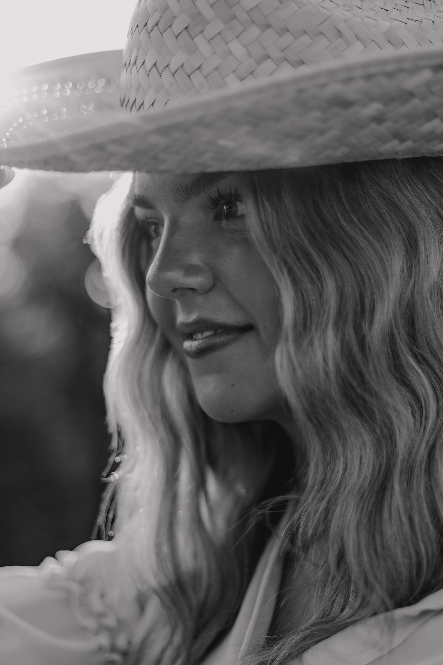 Close-up black and white portraits showing a straw hat and flowing hair in natural light.