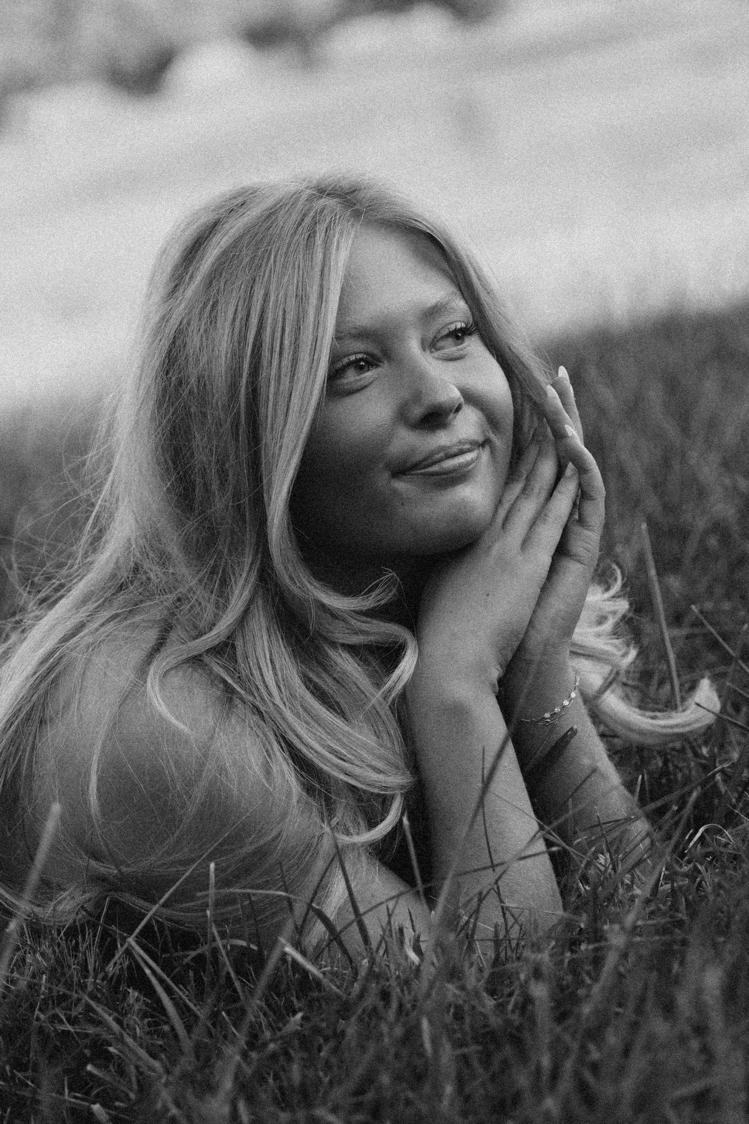 A series of black and white photos showing someone lying in grass with candid expressions and flowing blonde hair.