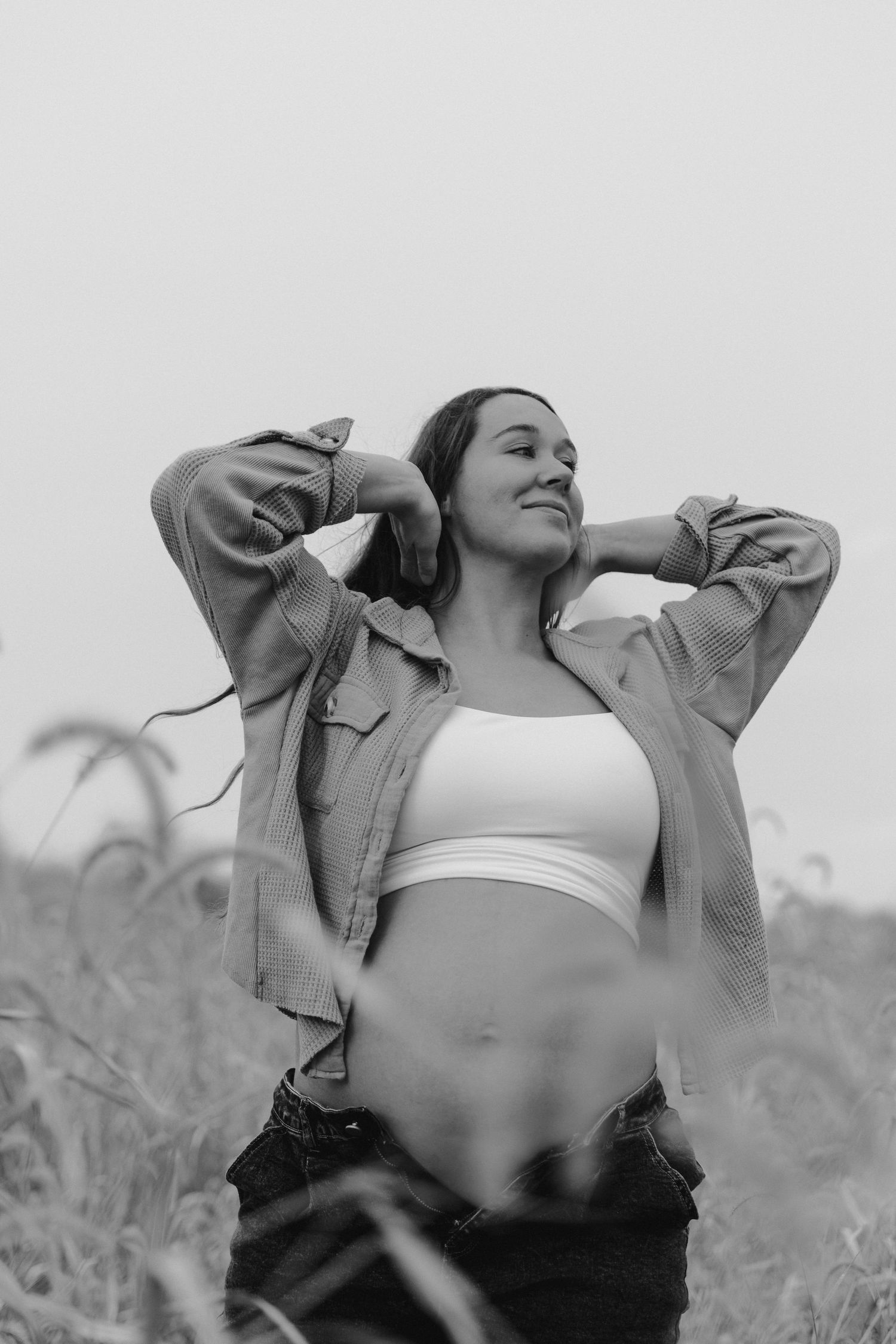 Black and white photo series of a person in a crop top and jacket dancing joyfully in a field.