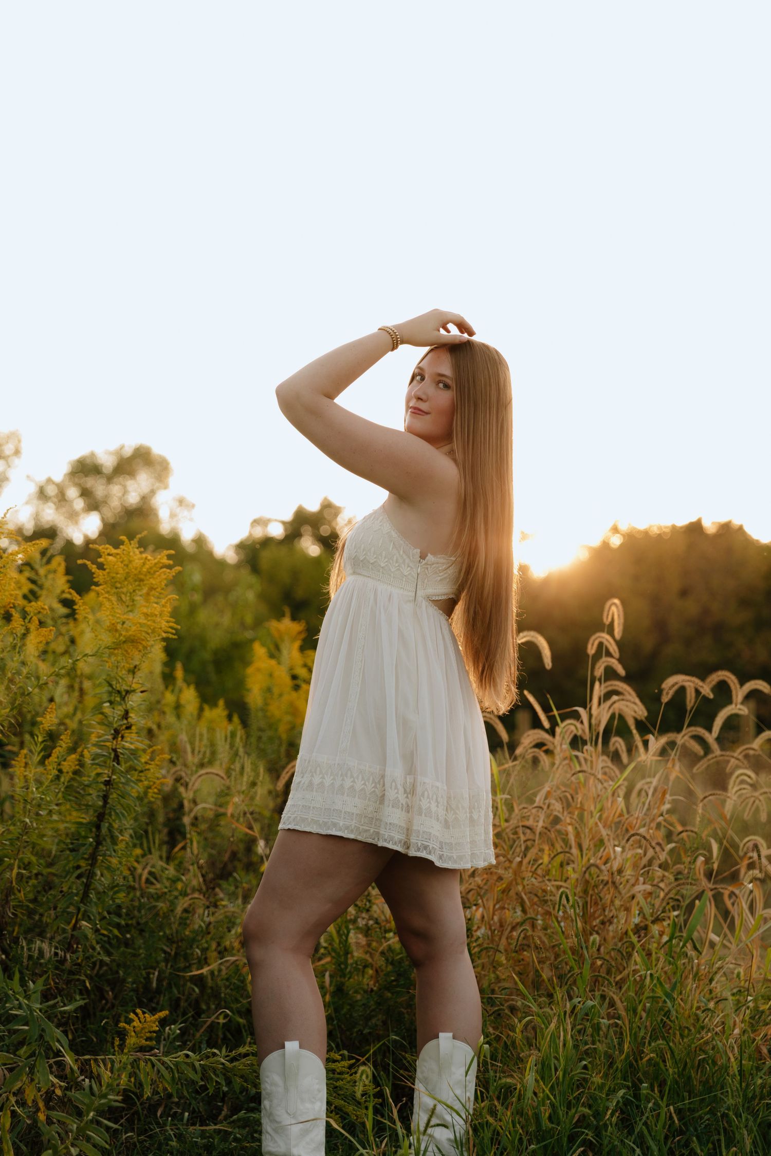 A dreamy summer scene with a person in a white dress and knee-high socks standing in a golden field at sunset.